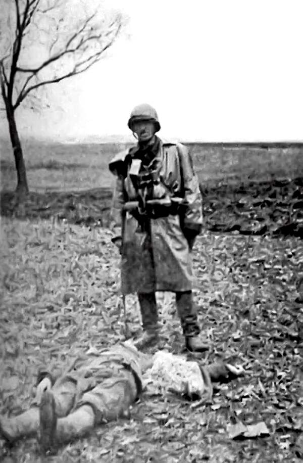 Солдат с польской партизанской Армии краевой позирует над трупом украинского крестьянина, убитого в поле у ​​села Сагринь на Холмщине, март 1944