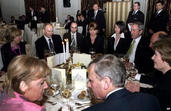 Анґела Меркель із тодішнім генсекретарем НАТО Яапом де Гооп Схеффером на передньому плані, Володимир Путін – на задньому плані другий зліва, Джордж Буш – третій справа, відвідують рецепцію у Бухаресті під час саміту НАТО у 2008 році