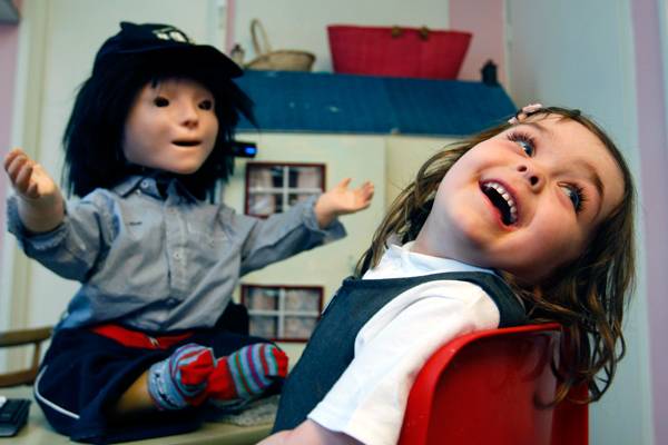 Девочка с аутизмом реагирует на эмоцию радости, которую показывает робот. Фото: Alastair Grant / AP