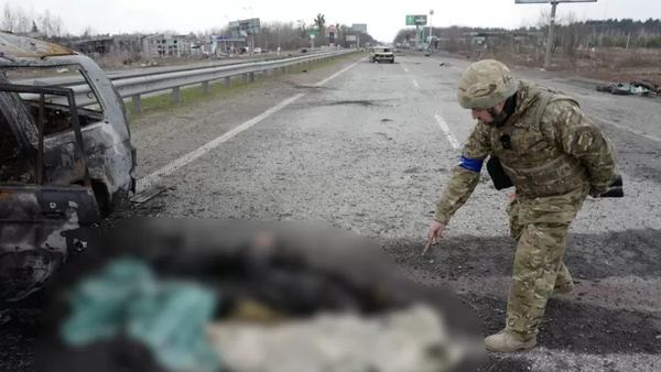 ФОТО,JEREMY BOWEN / Украинский военный показывает на обгоревшие человеческие останки у сгоревшего автомобиля