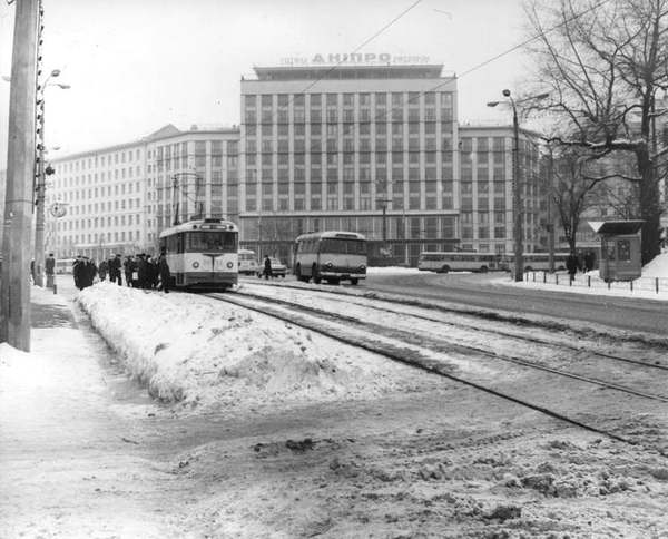 1970 год Площадь Ленинского комсомола (Европейская). Люди садятся в трамвай на остановке возле филармонии. Эта трамвайная линия, открытая 1 (13) июня 1892 года на Александровском (Владимирском) спуске, была самой первой в Киеве да и во всей Российской империи. Движение по ней закрыли в 1977 году, но рельсы еще долго не демонтировали (убрали уже в 1980-е).