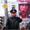 Полицейский говорит по сотовому на фоне плаката с Депардье