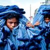 Двое работников несут охапки джинсов на рынок в Дакке в Бангладеш. Это фото Мушфикула Алама получило приз в категории «13 часов»