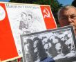  Учасник мітингу-реквієму тримає фото черепів та тлі плаката із зображенням Стал