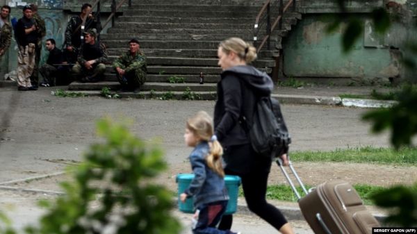 Фото:  Жінка з дитиною тікає з кварталу, в якому триває бій між прикордонним під