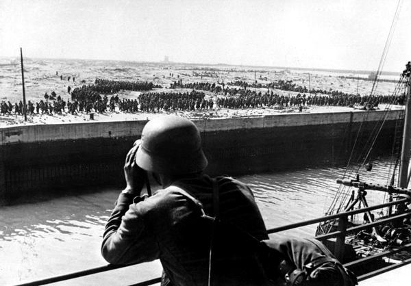 Фото:  Солдат вермахта смотрит в бинокль на французских и британских пленных